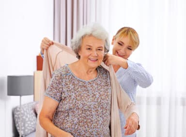 caregiver helping her patient with her clothes