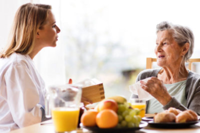 physicians talking to senior woman with healthy foods in the table