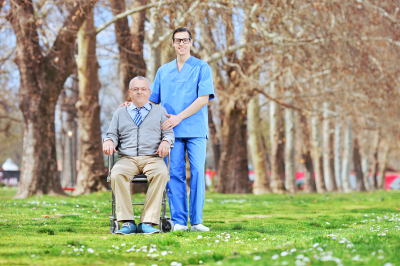 caregiver wearing eye glasses and senior man sitting in the wheelchair smiling