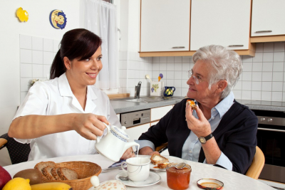 caregiver preparing meals to senior woman wearing eyeglasses smiling